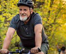 Elderly man wearing helmet rides a bike