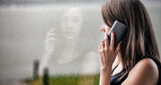 Woman staring at window reflection while on the phone