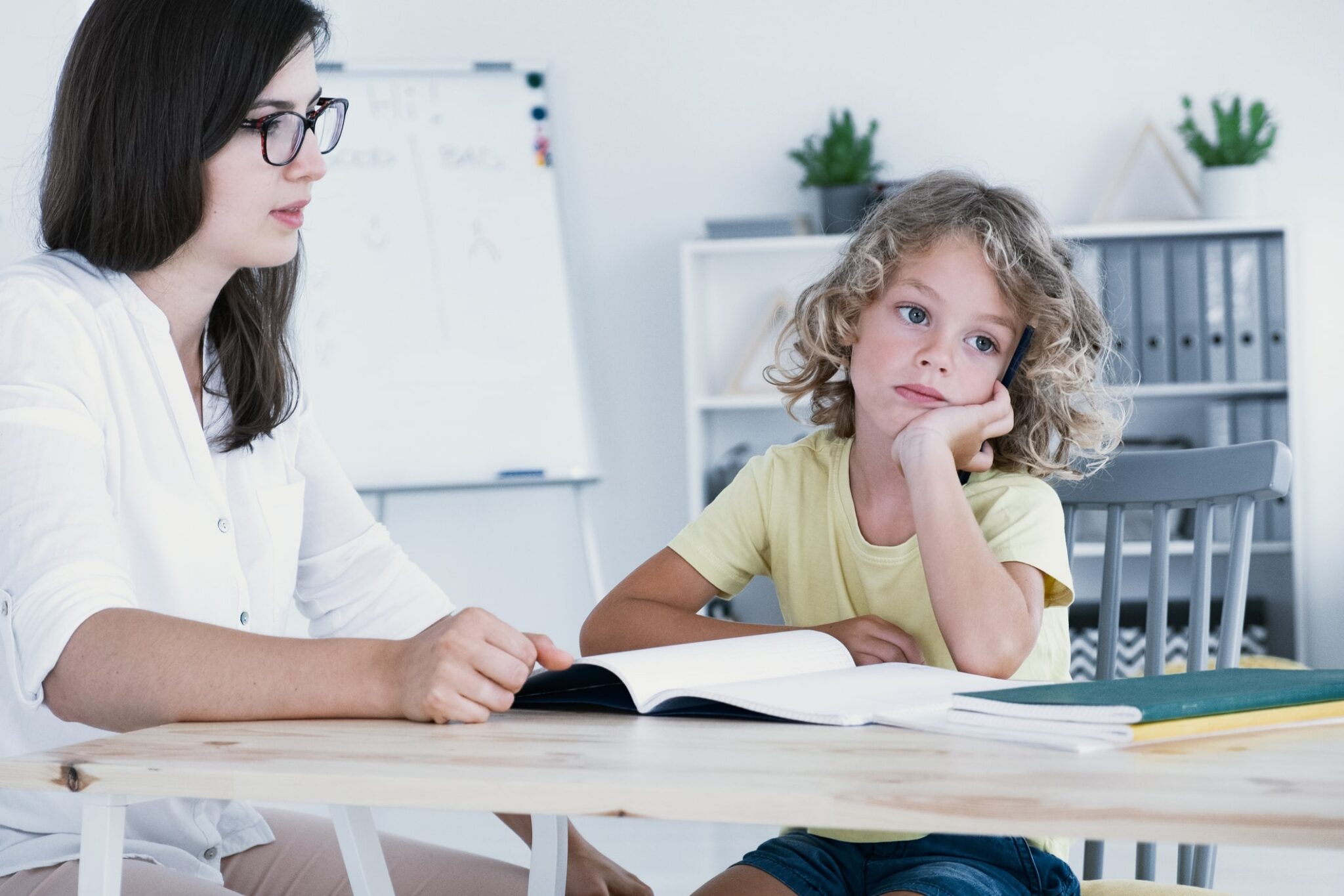 teacher observing a child that looks bored while staring into the distance