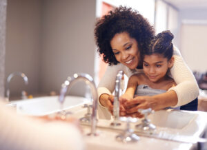 mom helping her daughter to wash her hands to prevent measles and other contagious diseases