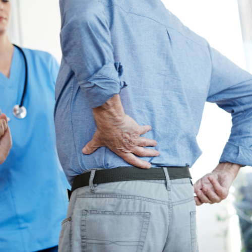 Man holding his hand on his back due to pain as he enters a doctor's office for a medial branch block.