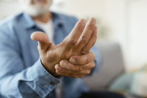 Man experiencing severe rheumatoid arthritis pain and rubbing his hand